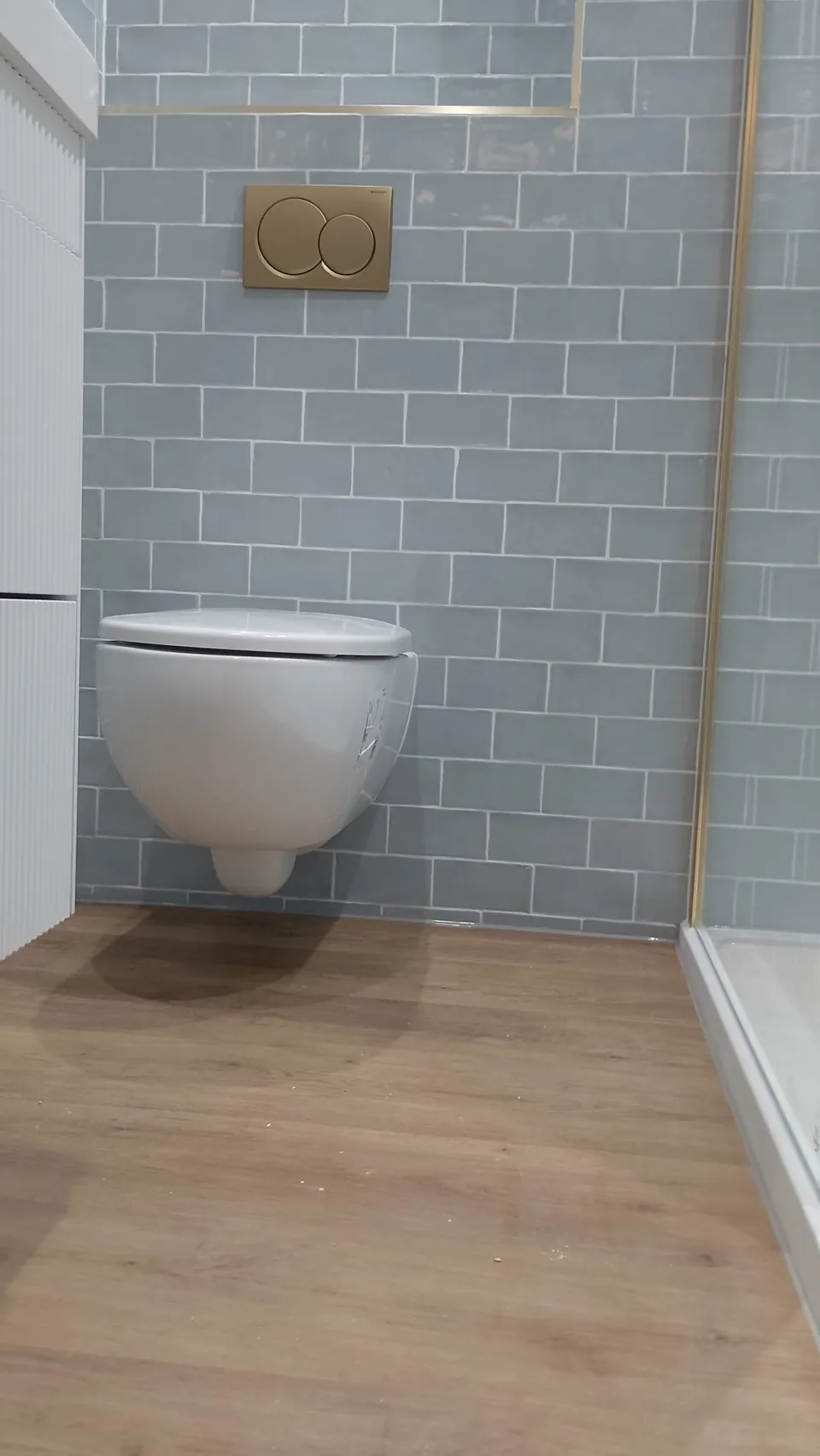 Wall-hung toilet against blue tiled bathroom walls